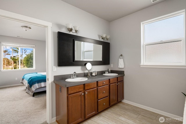 ensuite bathroom featuring a sink, baseboards, ensuite bathroom, and double vanity