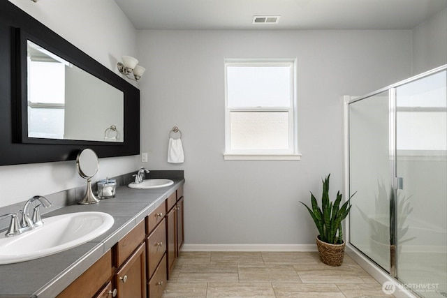 full bathroom with a sink, visible vents, a stall shower, and double vanity