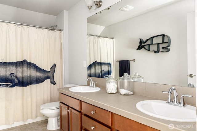 bathroom with a sink, visible vents, toilet, and double vanity