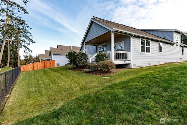 back of house featuring a yard, covered porch, and fence