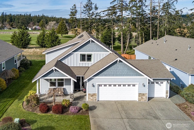 view of front of home featuring board and batten siding, a front lawn, concrete driveway, a garage, and stone siding