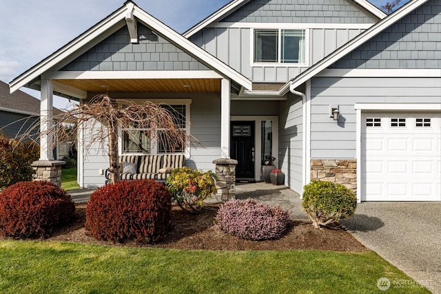 property entrance featuring a porch, stone siding, an attached garage, and board and batten siding