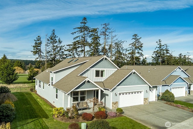 craftsman-style house with driveway, fence, board and batten siding, an attached garage, and a front yard
