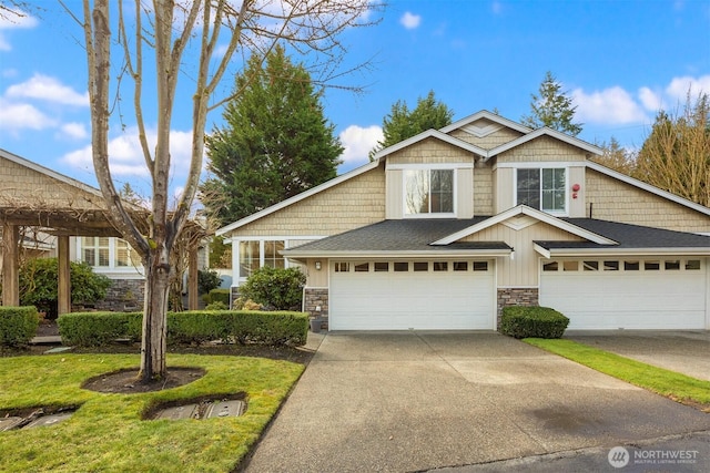 view of front of home featuring driveway, stone siding, a shingled roof, and a garage