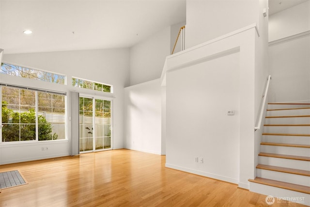 interior space featuring stairs, high vaulted ceiling, wood finished floors, and baseboards