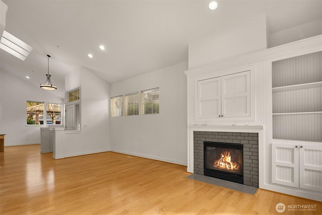 unfurnished living room with baseboards, light wood-style floors, a fireplace, high vaulted ceiling, and recessed lighting