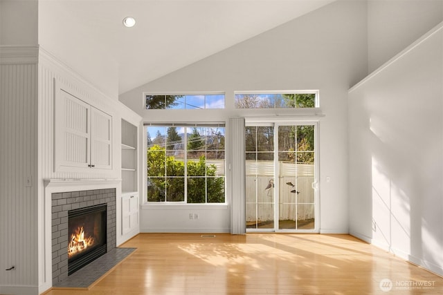 entryway featuring light wood finished floors, recessed lighting, a brick fireplace, high vaulted ceiling, and baseboards