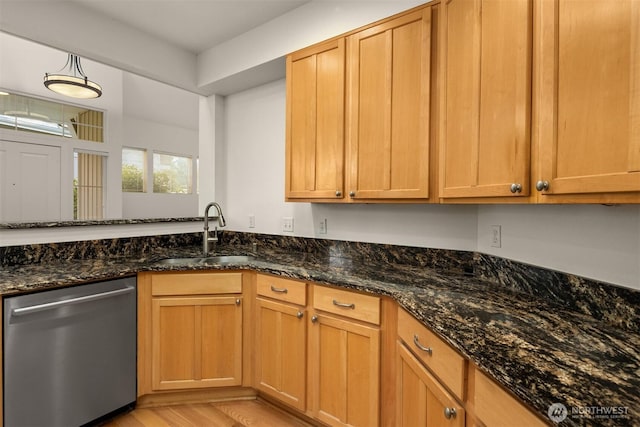 kitchen with dark stone counters, dishwasher, light wood-style flooring, and a sink