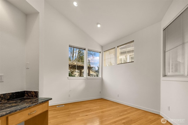 interior space featuring visible vents, vaulted ceiling, light wood-style flooring, and baseboards