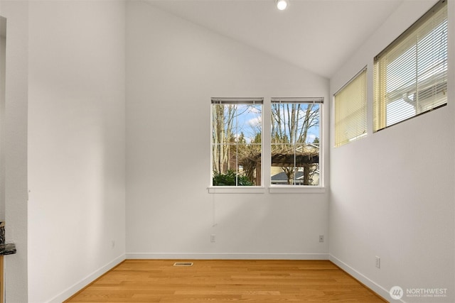 spare room with light wood-style flooring, visible vents, baseboards, and vaulted ceiling