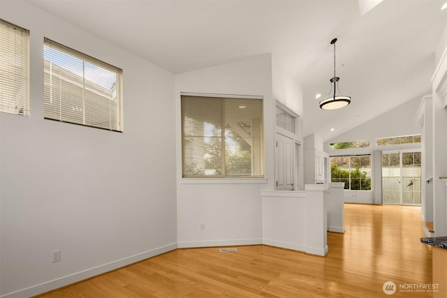 unfurnished room featuring lofted ceiling, light wood-style floors, visible vents, and baseboards