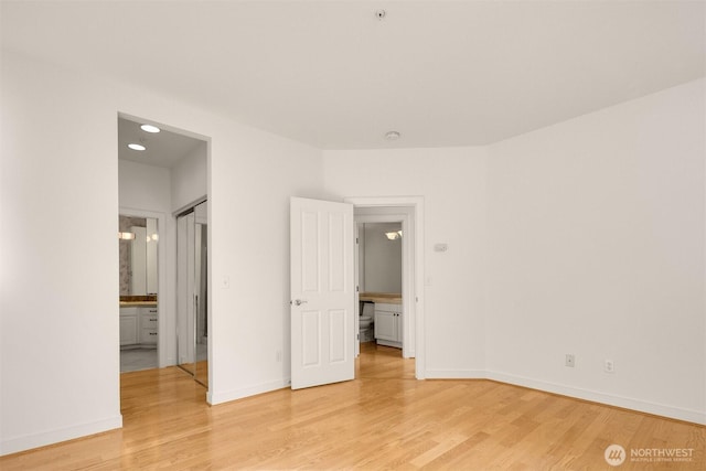 unfurnished bedroom with light wood-type flooring, ensuite bath, and baseboards