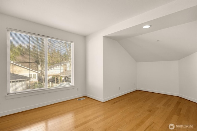 additional living space featuring baseboards, visible vents, vaulted ceiling, light wood-style floors, and recessed lighting