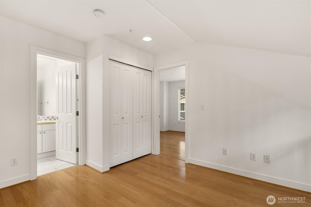 interior space with light wood-style floors, ensuite bath, baseboards, and a closet