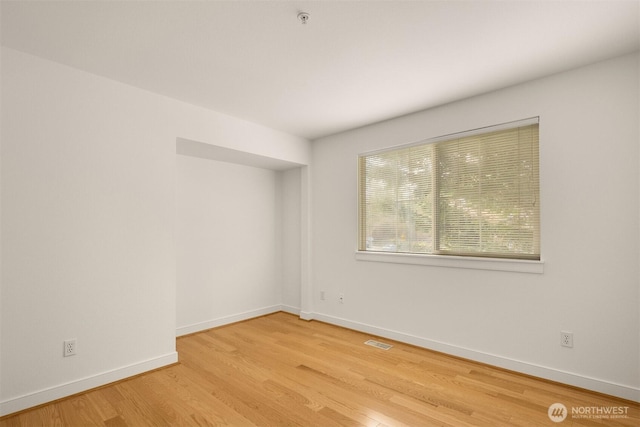 unfurnished room featuring visible vents, baseboards, and wood finished floors