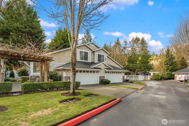 view of front facade featuring a front yard, stone siding, fence, and driveway