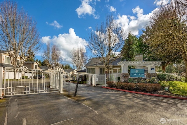 view of gate with fence, a residential view, and a pergola