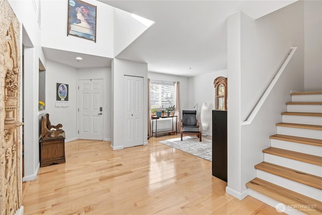 foyer featuring stairway, light wood-style flooring, and baseboards