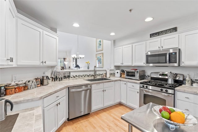 kitchen featuring light countertops, appliances with stainless steel finishes, a sink, and white cabinets