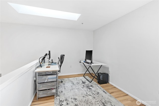 home office featuring light wood-type flooring, a skylight, and baseboards