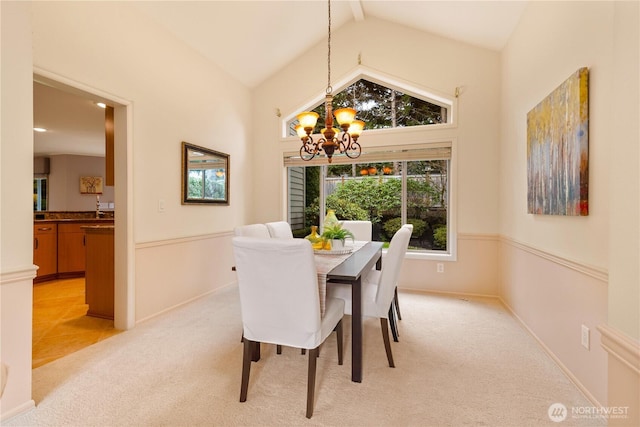 dining area with baseboards, light carpet, high vaulted ceiling, and a chandelier