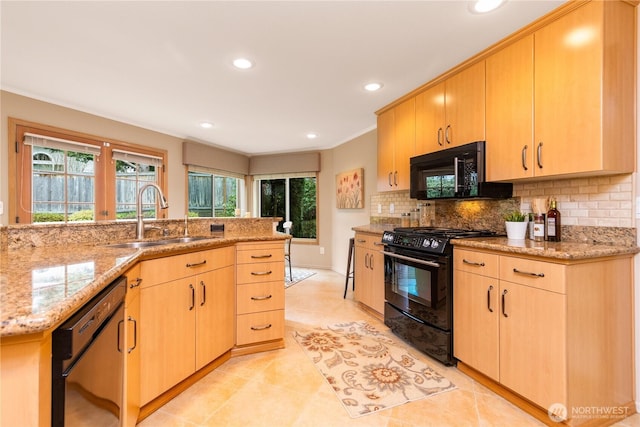 kitchen featuring light stone counters, light brown cabinetry, a sink, black appliances, and backsplash