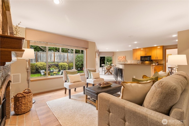 living area with recessed lighting, baseboards, light wood-style floors, and a brick fireplace