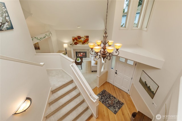 entrance foyer featuring light wood finished floors, stairway, a tile fireplace, and a notable chandelier