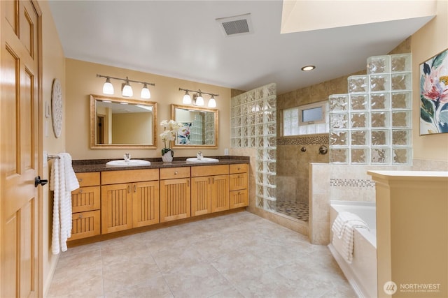 bathroom with visible vents, a sink, double vanity, walk in shower, and a bath