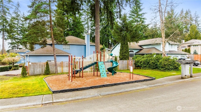 view of playground featuring a lawn and fence