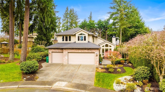 view of front of house featuring a front lawn, fence, concrete driveway, a garage, and brick siding