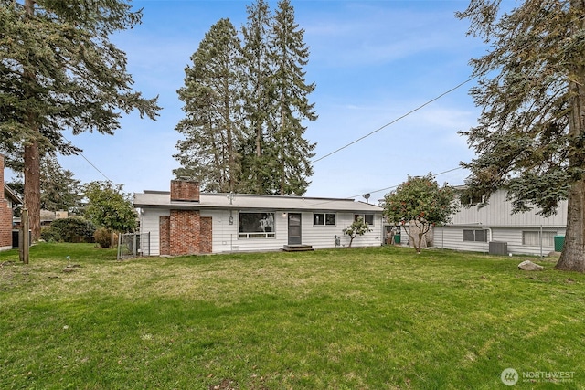 view of front of house with a chimney, central AC, and a front yard