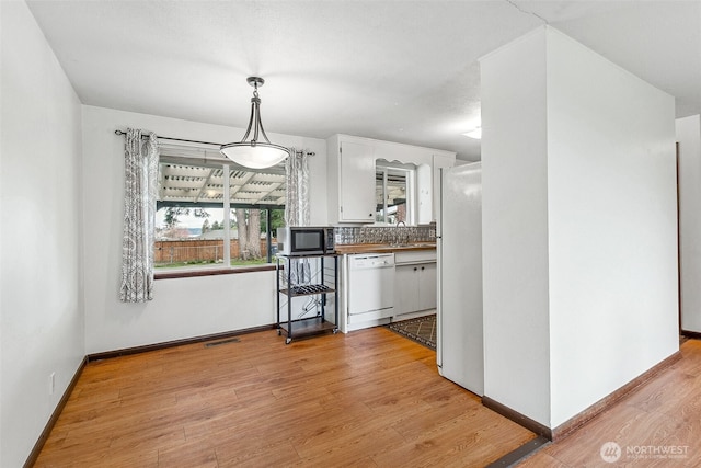 kitchen with white appliances, baseboards, light wood-style flooring, decorative backsplash, and white cabinetry