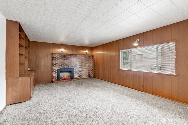 unfurnished living room featuring wood walls, a fireplace, and carpet