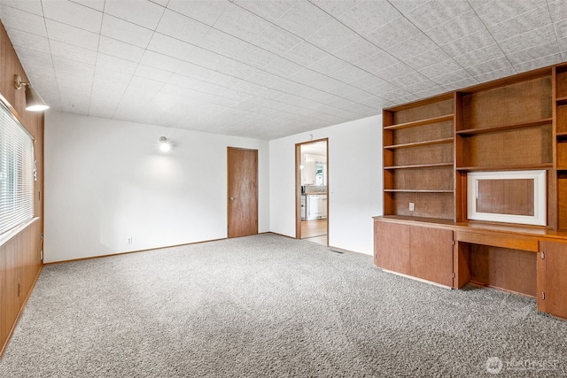 unfurnished living room with carpet and built in study area