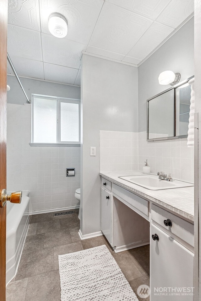 bathroom with tasteful backsplash, baseboards, shower / washtub combination, toilet, and vanity