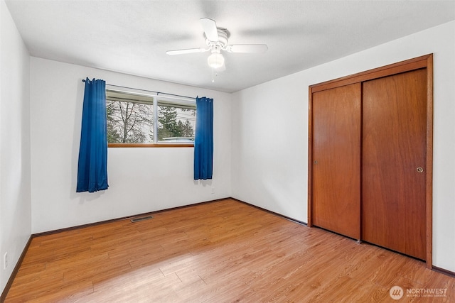 unfurnished bedroom featuring a closet, visible vents, ceiling fan, and wood finished floors