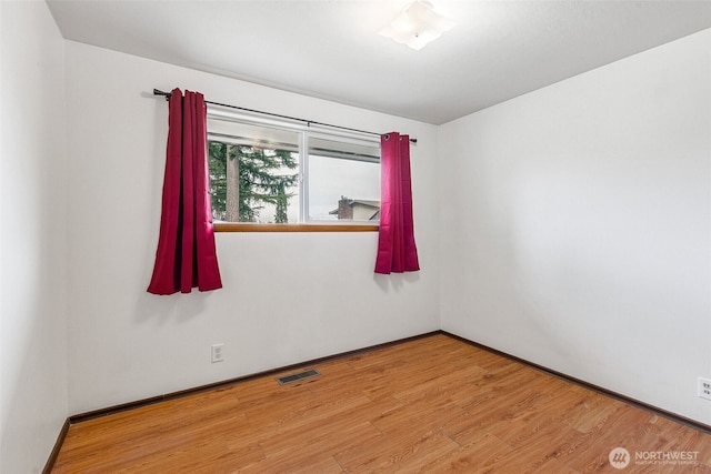 empty room featuring visible vents, baseboards, and wood finished floors