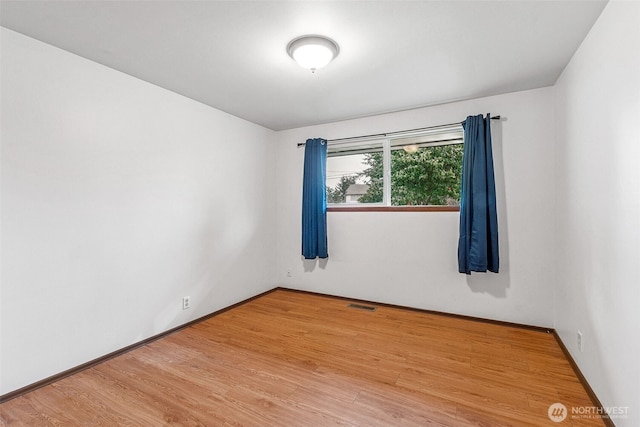 spare room with visible vents, baseboards, and wood finished floors