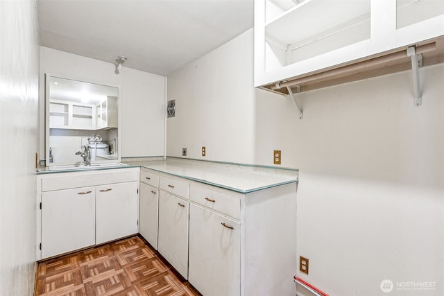 kitchen with white cabinets, light countertops, and a sink