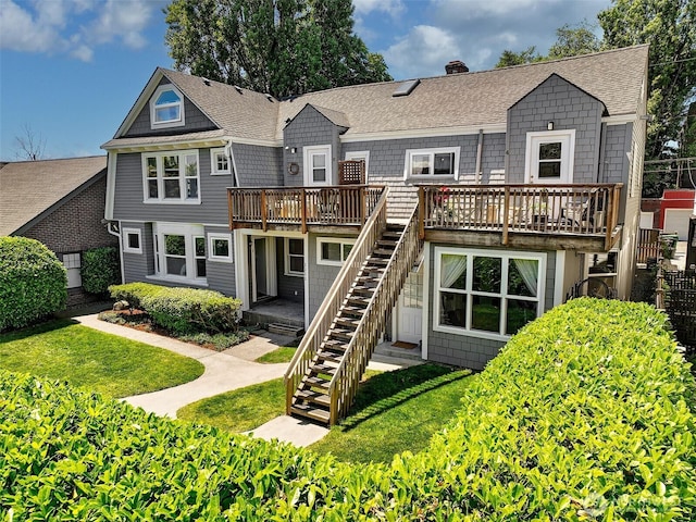 back of house featuring a yard, stairway, roof with shingles, a wooden deck, and a chimney