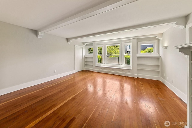 unfurnished room featuring wood-type flooring, baseboards, and beam ceiling