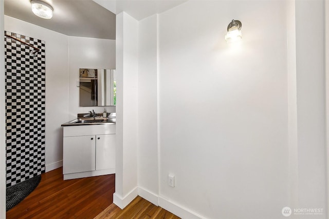 full bathroom with baseboards, a tile shower, wood finished floors, and vanity