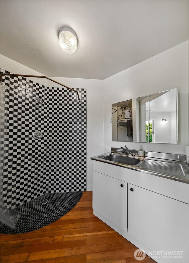 bathroom featuring vanity, wood finished floors, and tiled shower