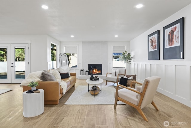 living room featuring french doors, a tile fireplace, light wood-style flooring, and recessed lighting