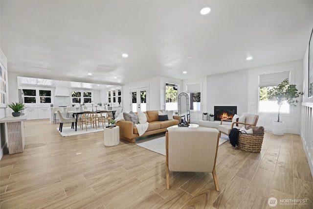 living room featuring light wood finished floors, a fireplace, and recessed lighting