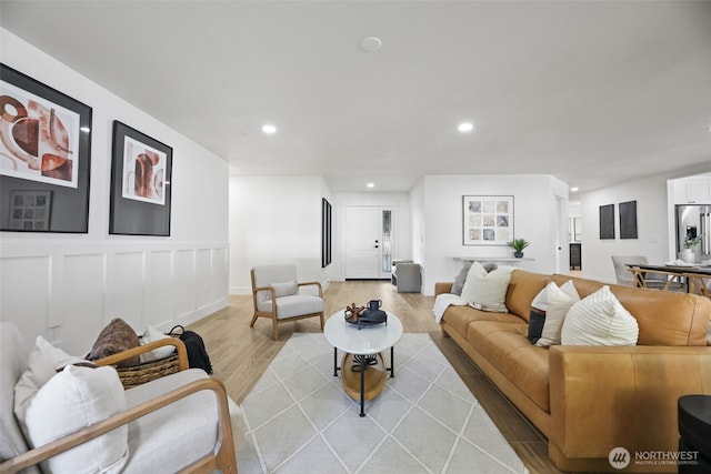 living room featuring light wood finished floors, a decorative wall, and recessed lighting