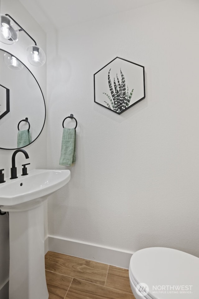 bathroom with baseboards, a sink, toilet, and wood tiled floor