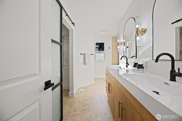 bathroom with visible vents, a sink, baseboards, and double vanity