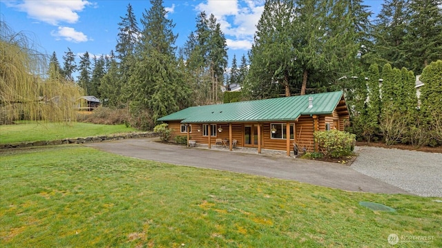 log cabin featuring a standing seam roof, a porch, a front lawn, log exterior, and metal roof